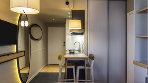 Hotellihuone, jossa on sänky, työpöytä ja kaksi tuolia, peili, televisio ja vaatekaappi.