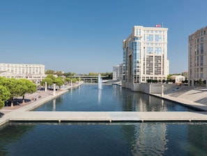 A modern building with a reflective glass facade, a water feature in the foreground, and a clear sky. - Aparthotel Adagio Access Montpellier Centre (Montpellier)