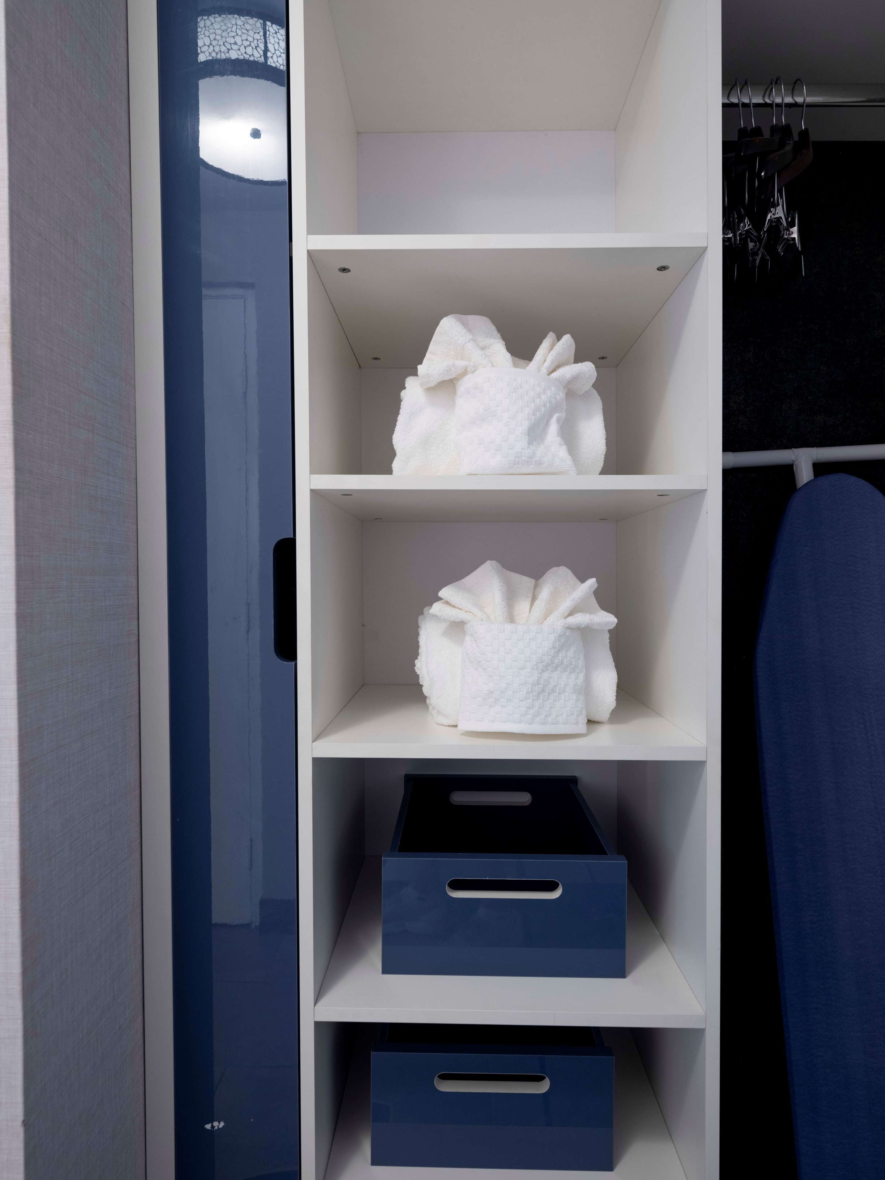 A closet with white shelves and blue storage boxes.