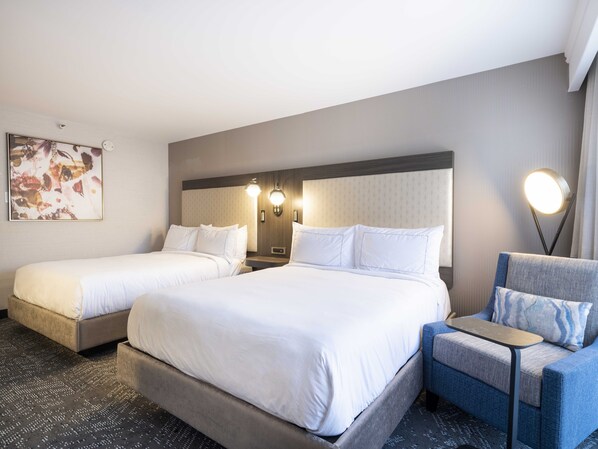 A hotel room with two single beds, a sofa, and a small table.