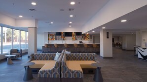 Un vest íbulo moderno con zona de bar, asientos y grandes ventanales.