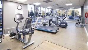 Un gimnasio con cintas de correr, elípticas y racks para pesas.