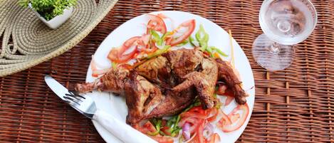 A plate of grilled chicken with vegetables on a wicker table.