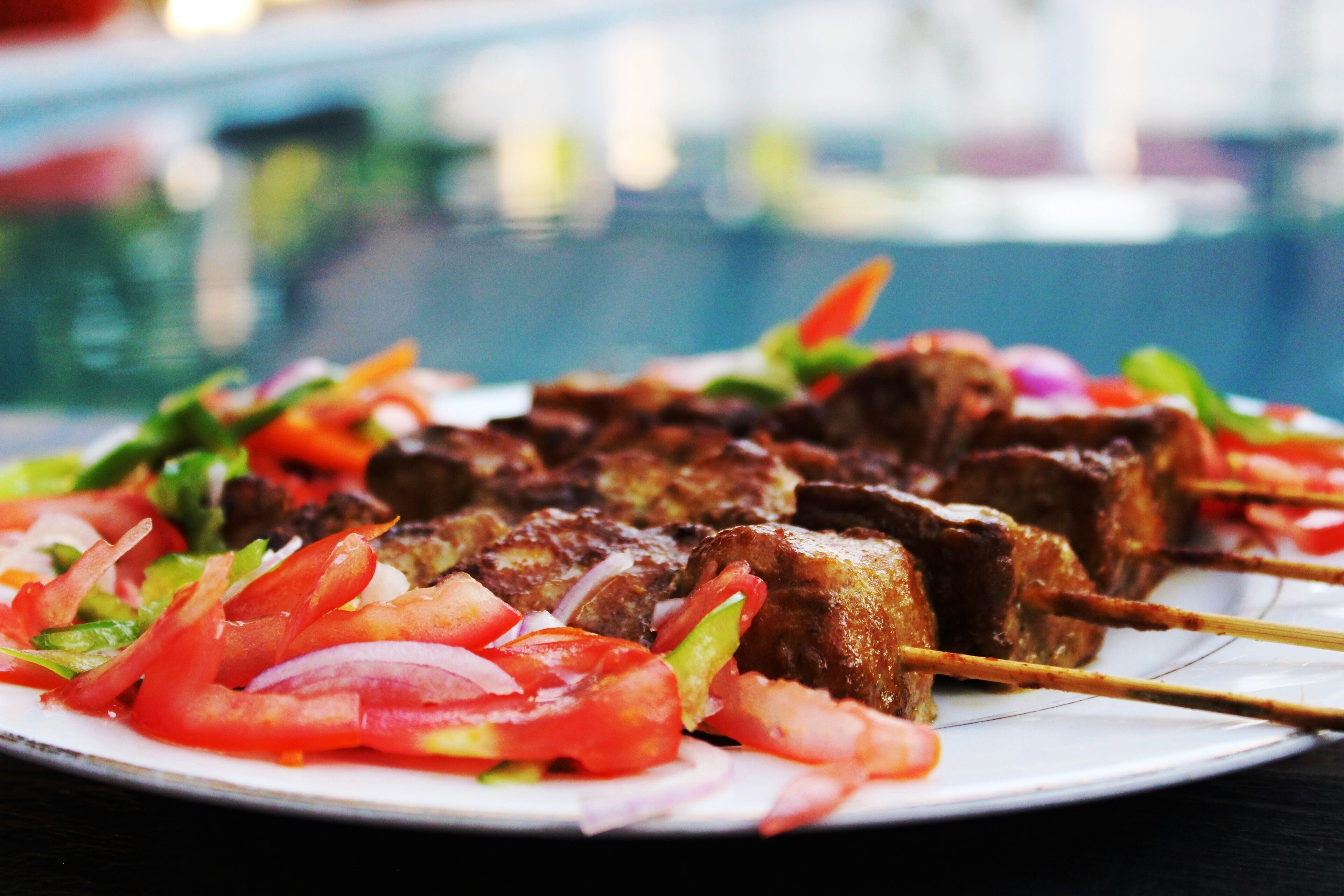 Skewered meat with vegetables on a plate.