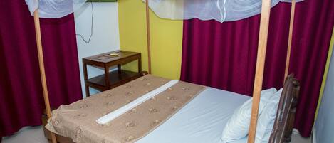Una cama individual con dosel, una mesita de noche de madera y un televisor instalado en la pared.