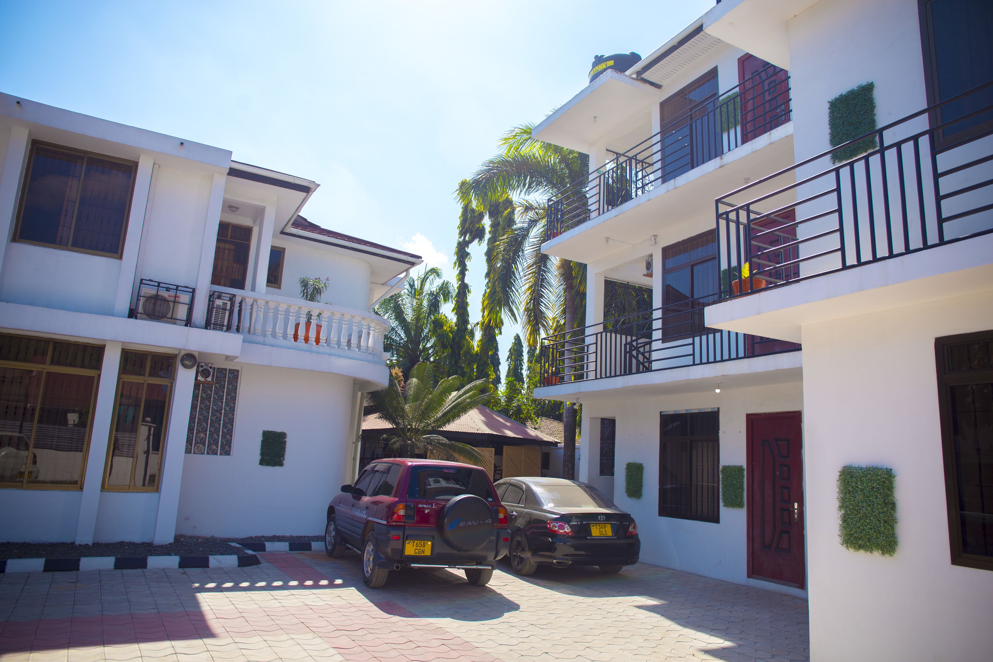 A residential building with a two-story structure, a covered parking area, and a red door.
