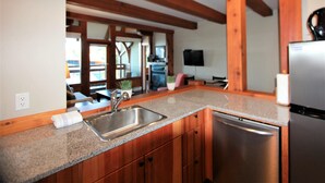 Una cocina con encimeras de granito, armarios de madera, pileta de acero inoxidable y lavavajillas integrado.