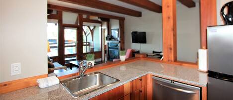 A kitchen with granite countertops, wooden cabinets, a stainless steel sink, and a built-in dishwasher.