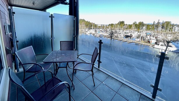 En balkong med ett bord och stolar, med utsikt över en småbåtshamn.