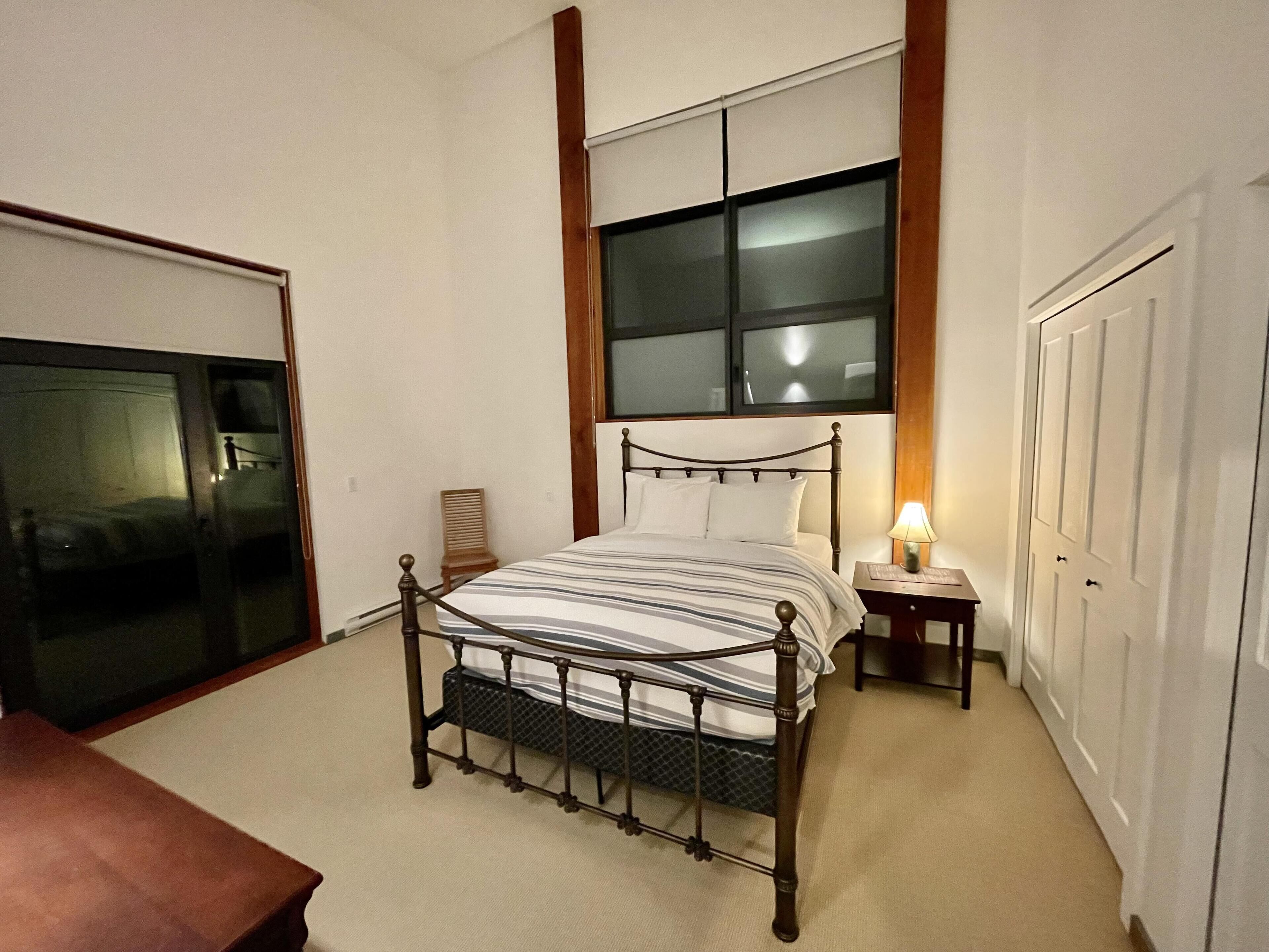 A bedroom with a bed, a nightstand, a chair, and a wardrobe.