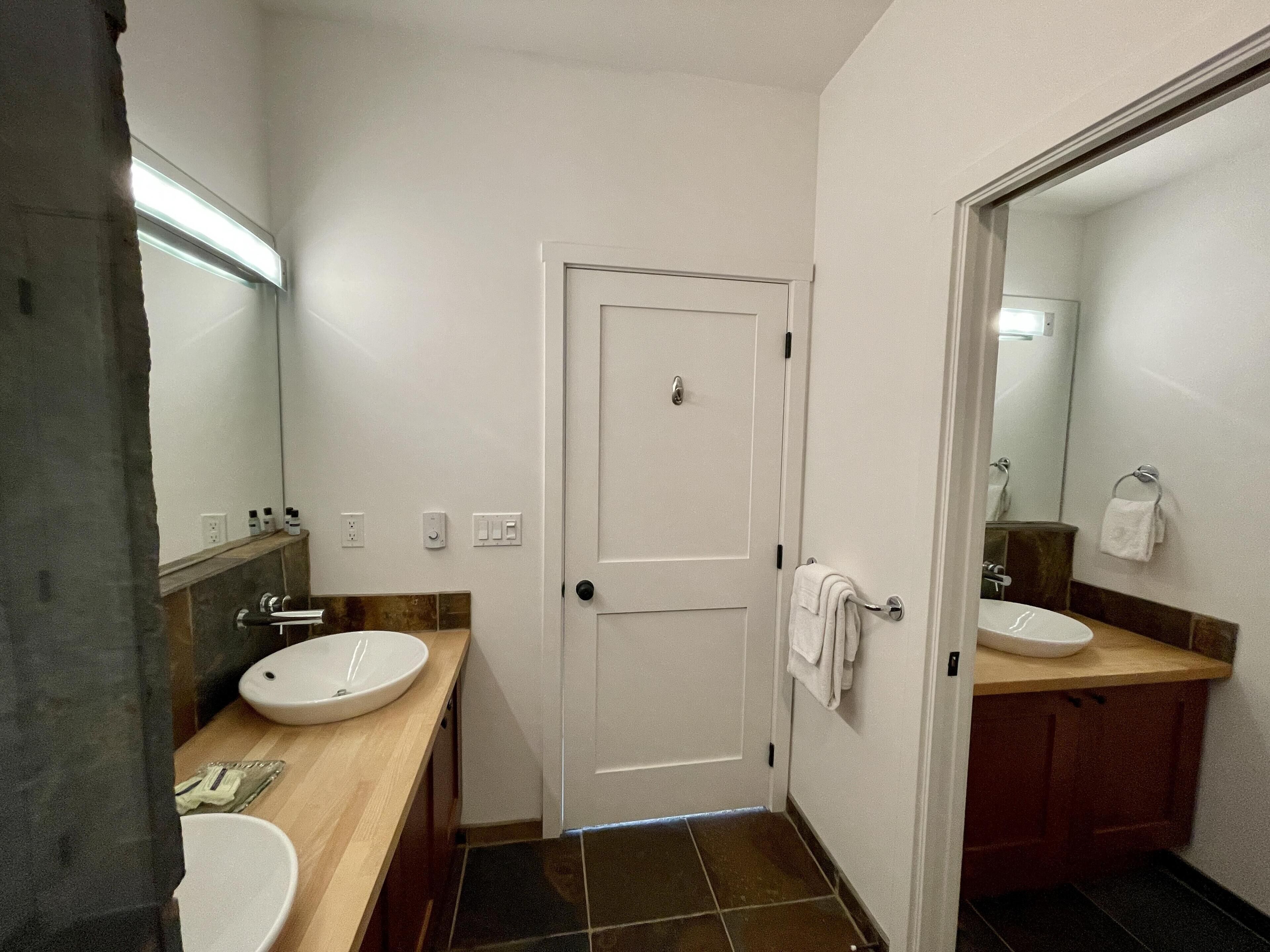 A bathroom with two sinks, a mirror, and a door.
