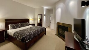A bedroom with a large bed, a television, a fireplace, and a mirror. - Big Beach Villa (Ucluelet)