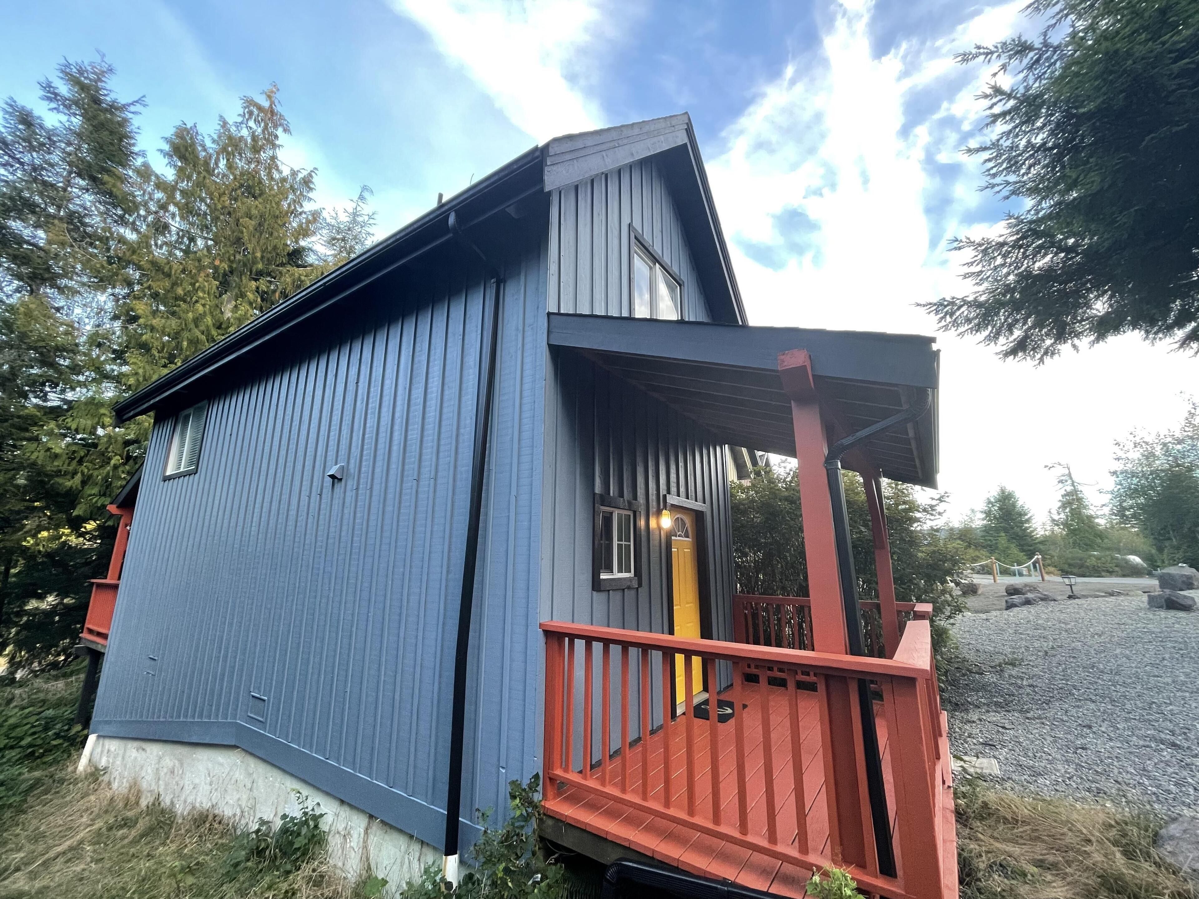 Un bâtiment en bois bleu, avec un porche rouge et une porte jaune.