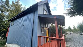 Un bâtiment en bois bleu, avec un porche rouge et une porte jaune.