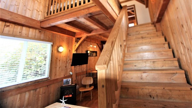 Una escalera de madera en una habitación estilo cabaña con un ventanal grande, un escritorio y una silla.