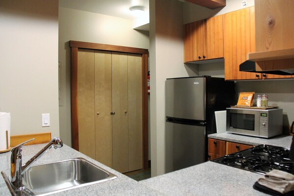 A kitchen with a stainless steel sink, a refrigerator, a microwave, and a stove.