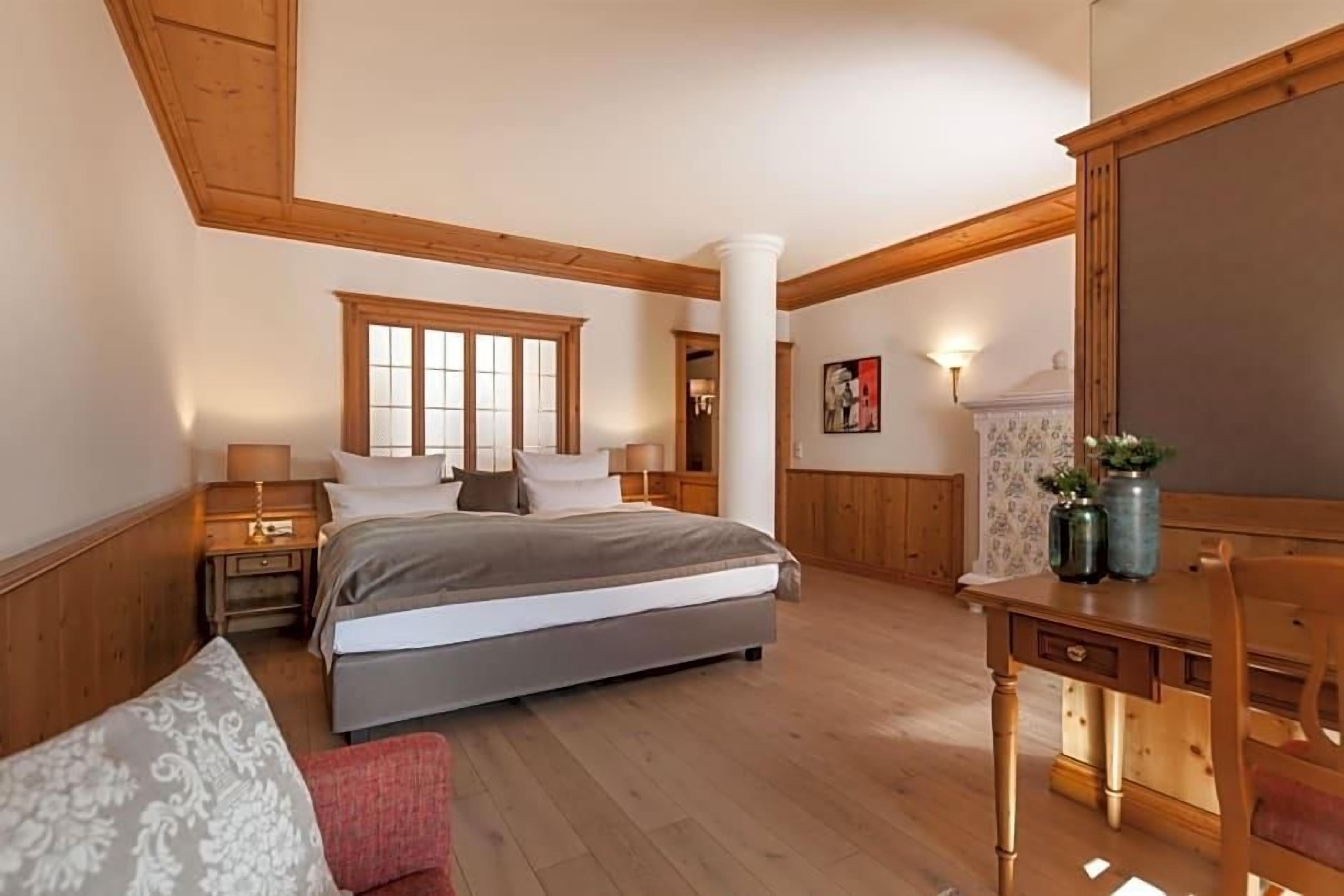 Ein Schlafzimmer mit einem großen Bett, einem Schreibtisch und einem Stuhl. Im Raum befindet sich ein Fenster und eine Tür.