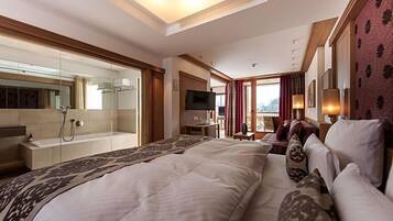A hotel room with a large bed, a television, a desk, and a shower area.