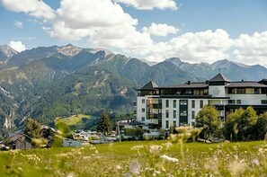 A hotel with a modern design, situated in a mountainous area with a view of the Alps.