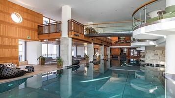 A modern indoor swimming pool with multiple levels and seating areas.