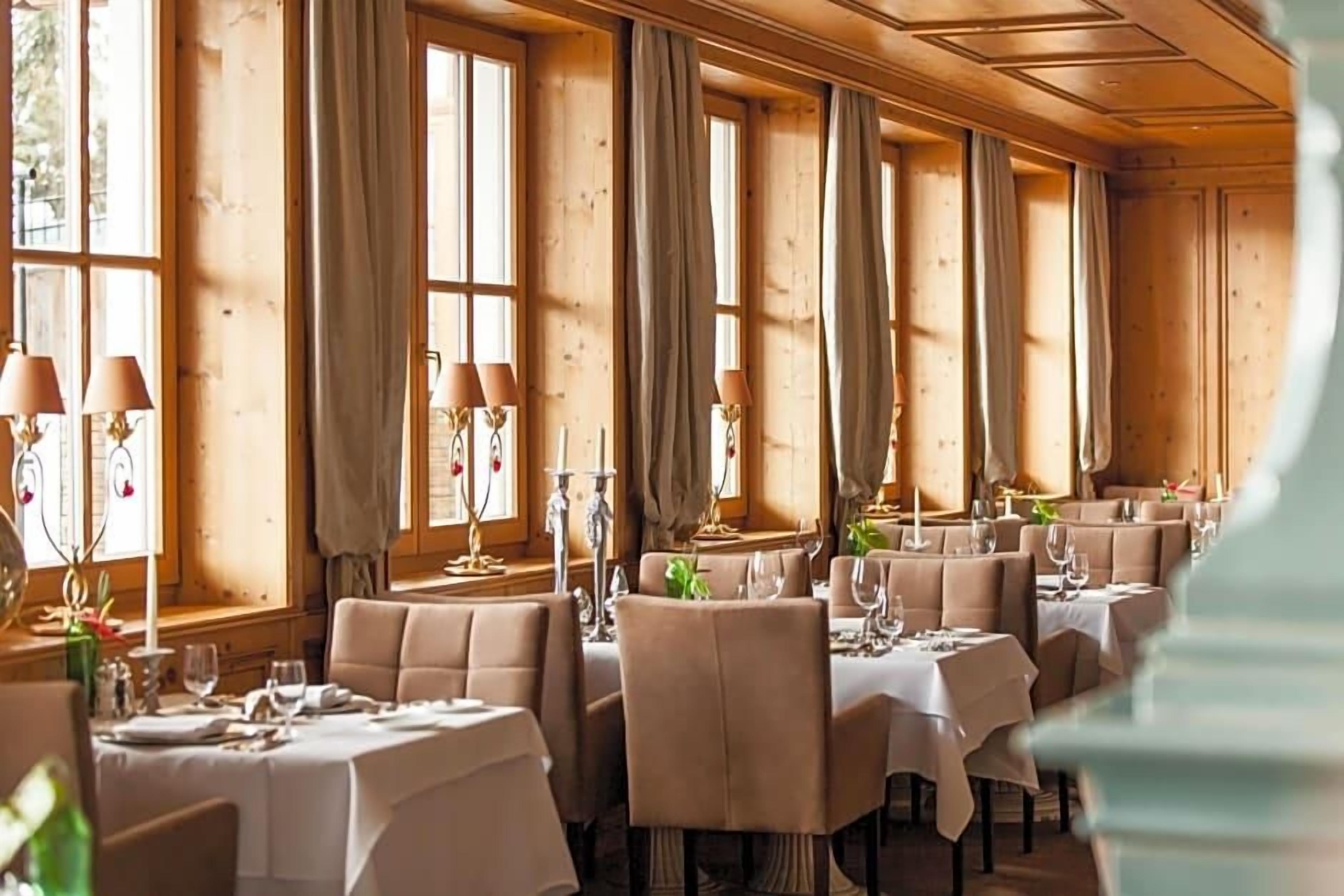 Ein Restaurant mit mehreren Tischen, gedeckt mit weißen Tischdecken und Kerzen.