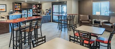 A modern restaurant with a bar area, seating arrangements, and a kitchen in the background.