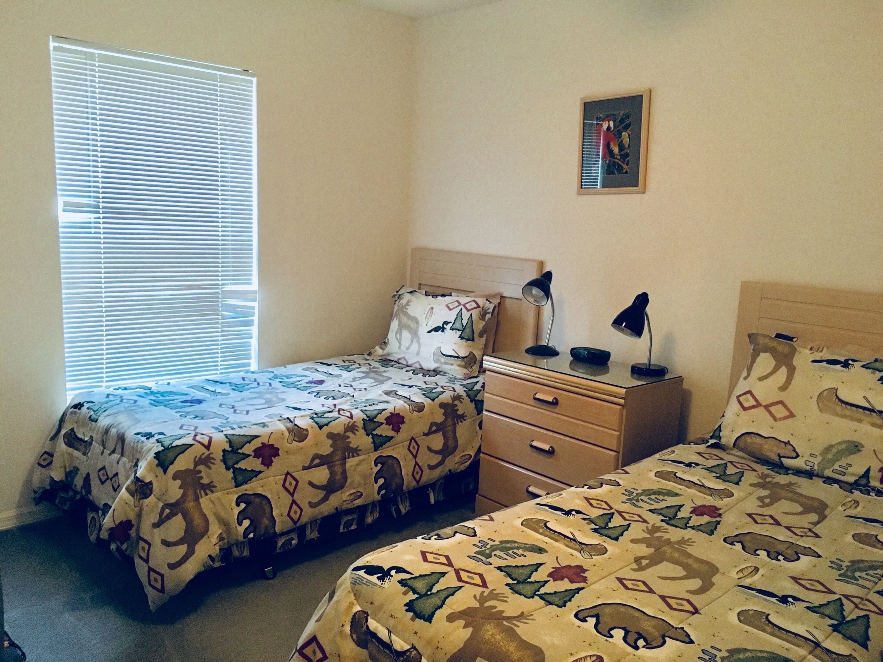 Ein Schlafzimmer mit zwei Betten, einem Nachttisch und einem Fenster mit Jalousien.