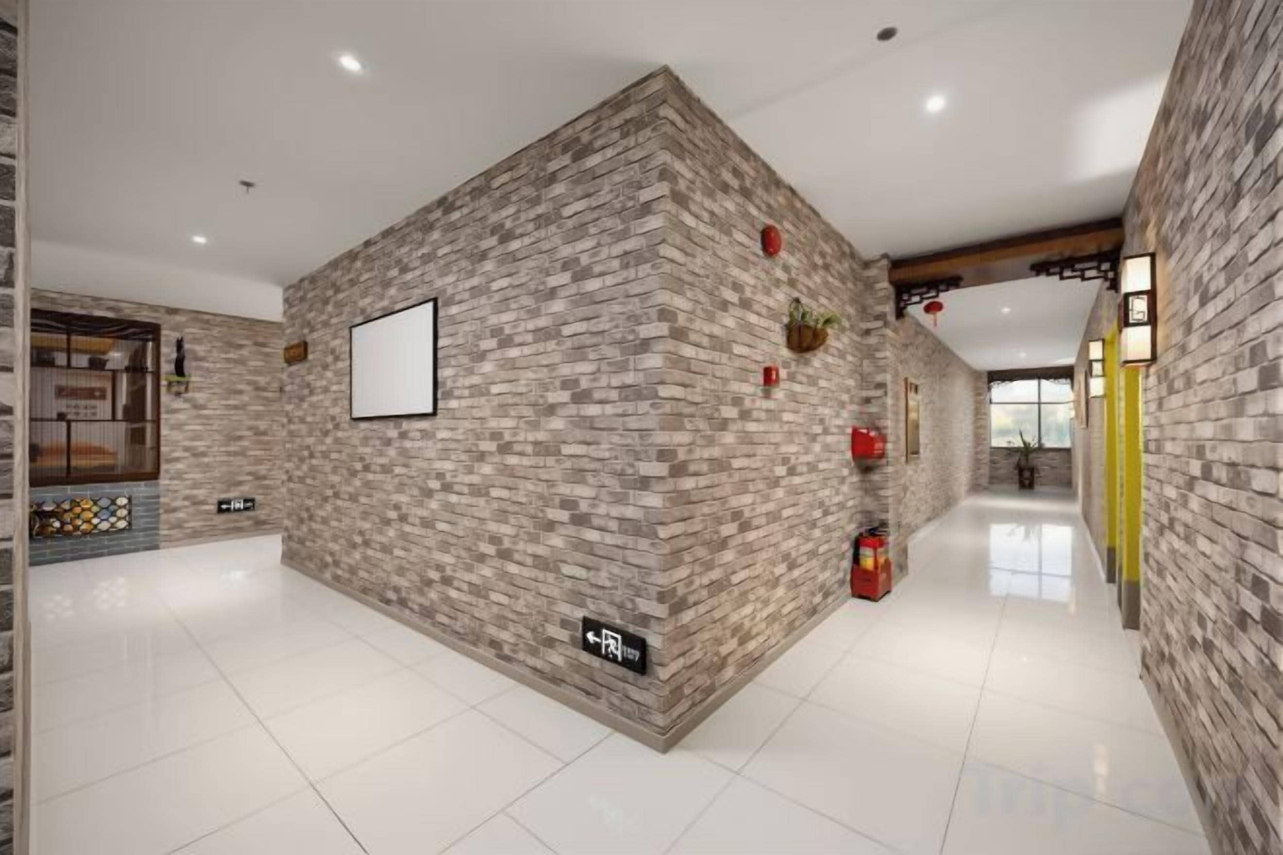 A hallway with a brick wall, a fire extinguisher, and a framed picture on the wall.