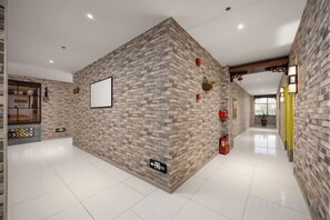 A hallway with a brick wall, a fire extinguisher, and a framed picture on the wall. - 8 Inn (Dongguan Dongkeng) (Dongguan)