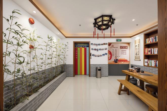 A reception area with a reception desk, a wall-mounted sign, a bookshelf, and a bench.