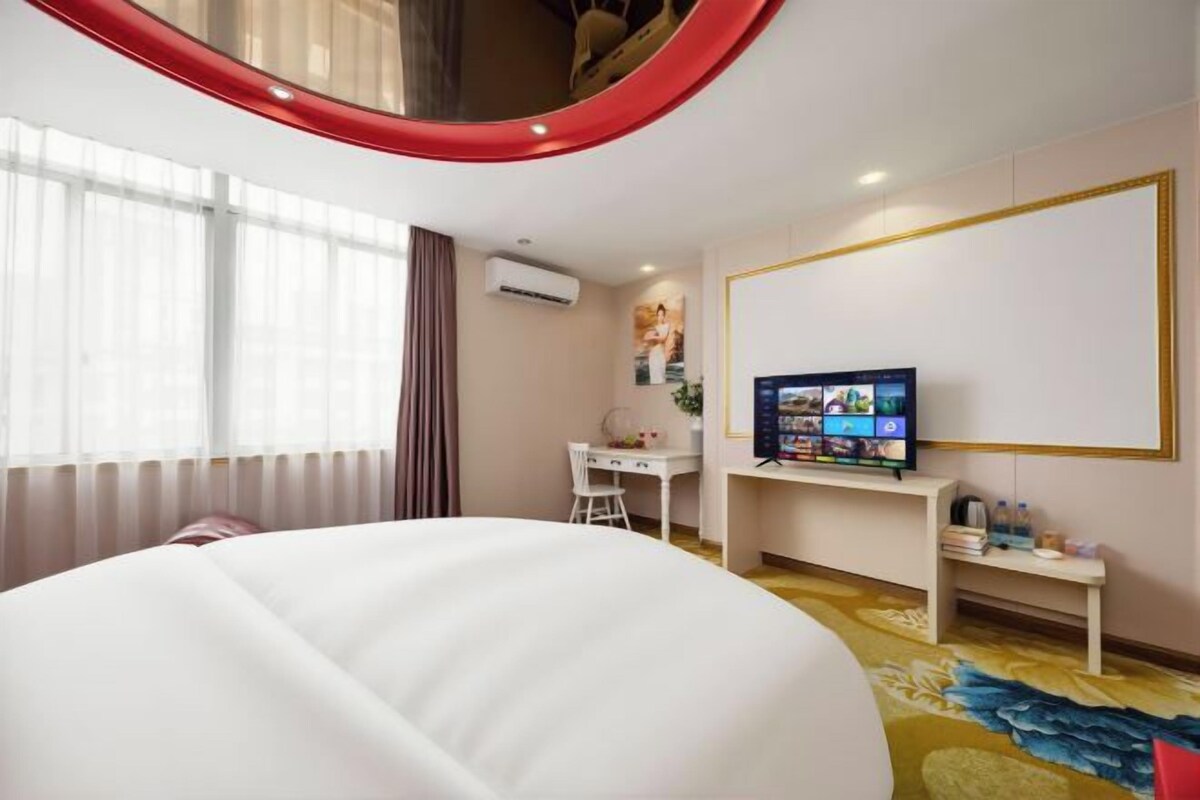 A hotel room with a bed, a desk, a television, and a large window.