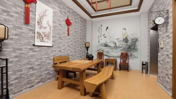 Un'area pranzo con un tavolo di legno e panche, una sveglia appesa al muro e un quadro.