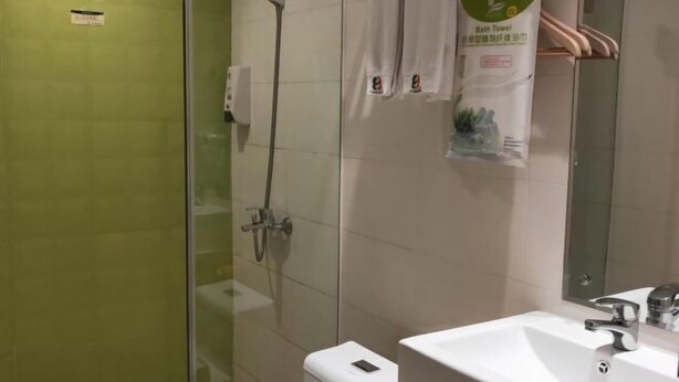 Un baño moderno con ducha de mampara de vidrio, lavamanos blanco y espejo.