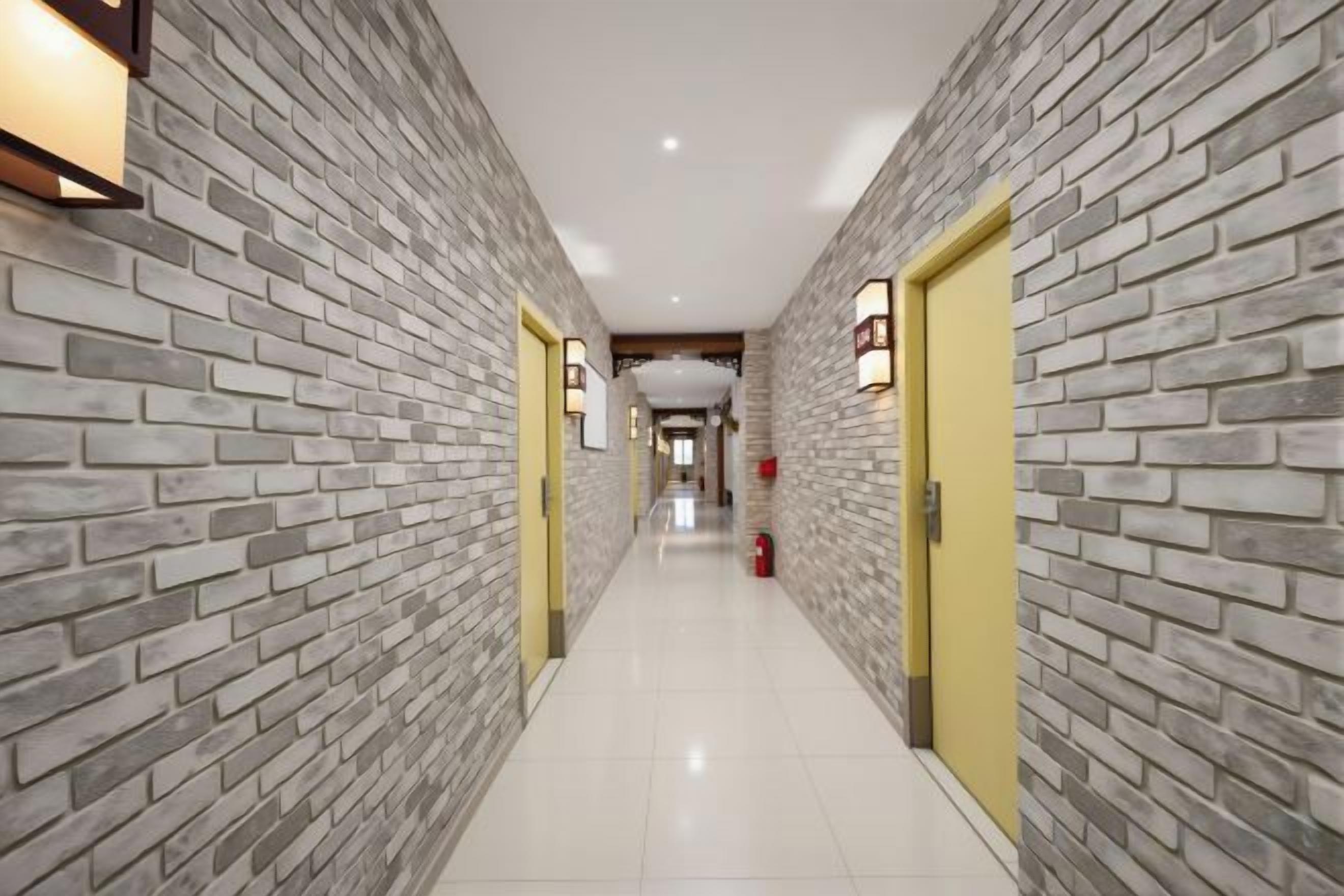 A corridor with brick walls, a yellow door, and a fire extinguisher.