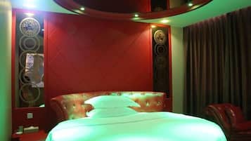 Quarto com cabeceira estofada, cama com roupa de cama branca e parede em destaque vermelha.
