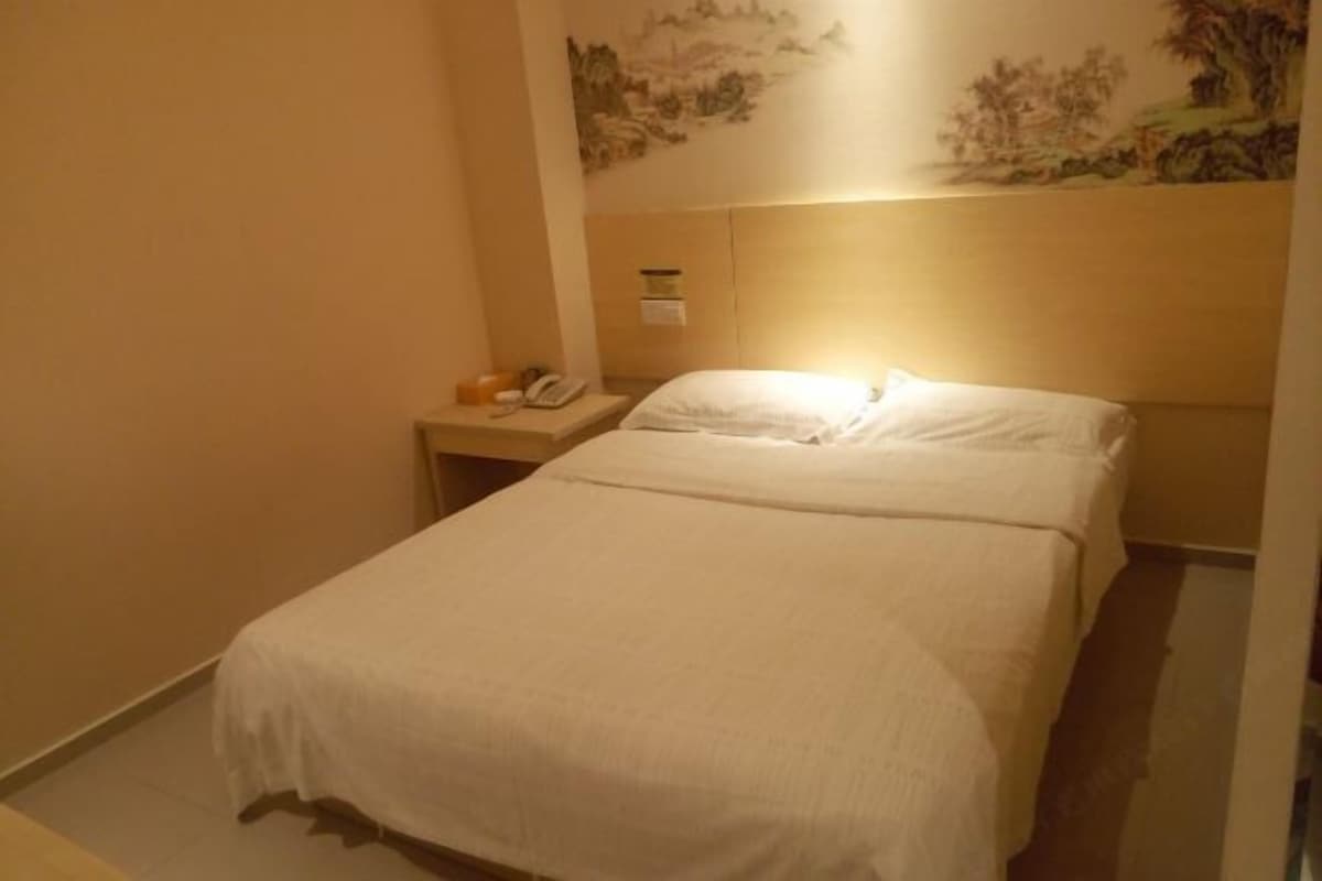 A neatly made bed with a white bedspread in a hotel room.