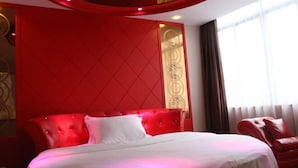 Una habitación de hotel con un cabecero tapizado en rojo, una colcha blanca y un sillón de cuero rojo.