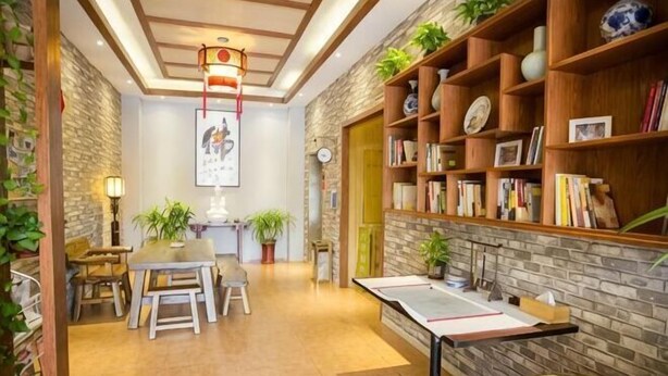 Um quarto aconchegante com uma mesa de jantar, cadeiras, uma estante de livros e um detalhe decorativo na parede.
