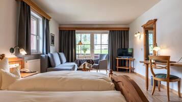 Ein Hotelzimmer mit Bett, Schreibtisch mit Computer, Fernseher und einer Sitzecke mit Sessel und Tisch.