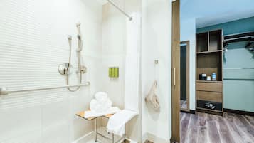 A modern bathroom with a glass shower enclosure, a towel rack, and a wooden vanity.