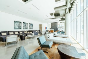 A spacious lobby with a modern design, featuring a seating area with sofas and armchairs, a coffee table, and a large window providing a view of the outside. - Hilton Garden Inn Denver Union Station, CO (Denver)