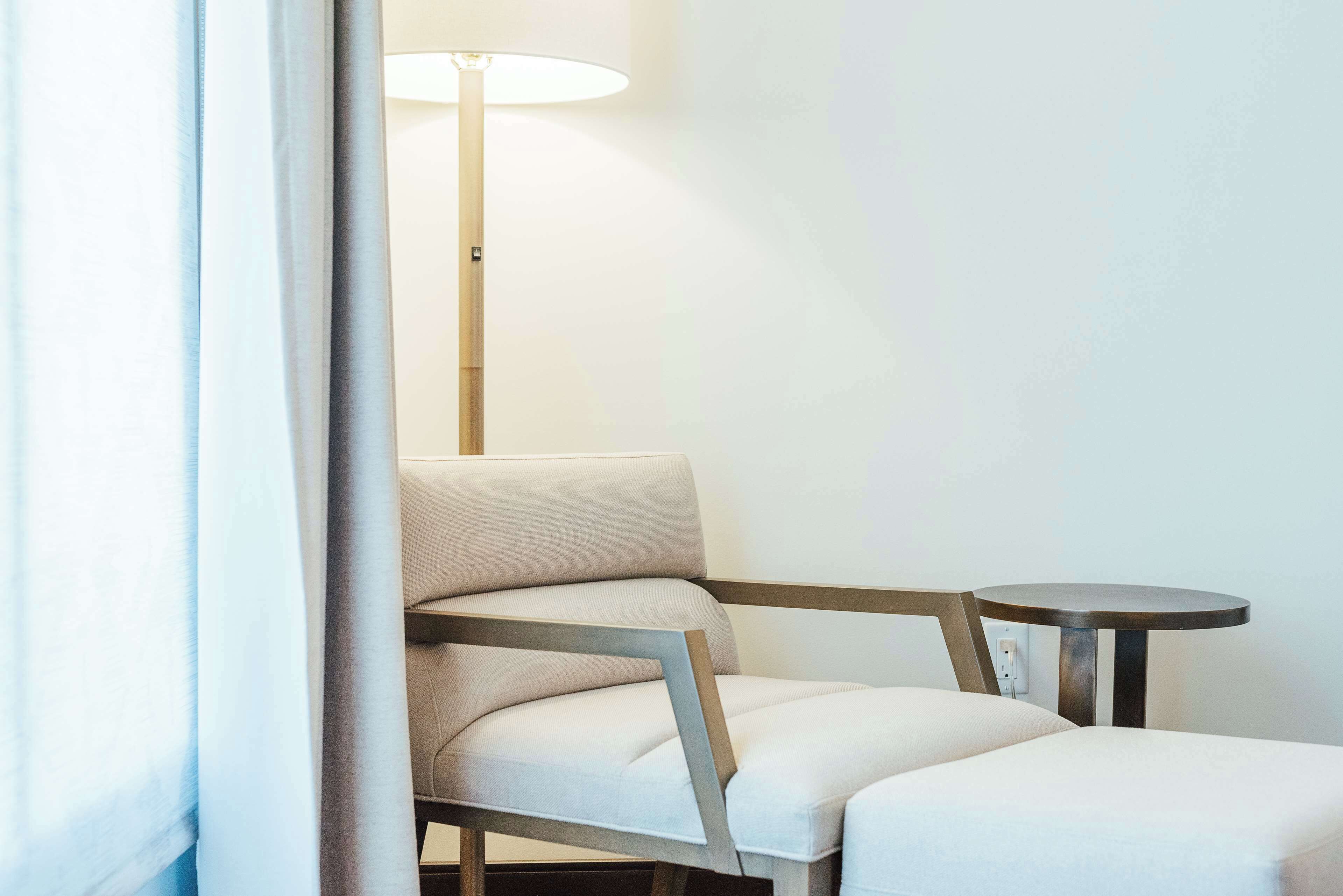 Una habitación moderna con una silla minimalista y una pequeña mesa redonda.
