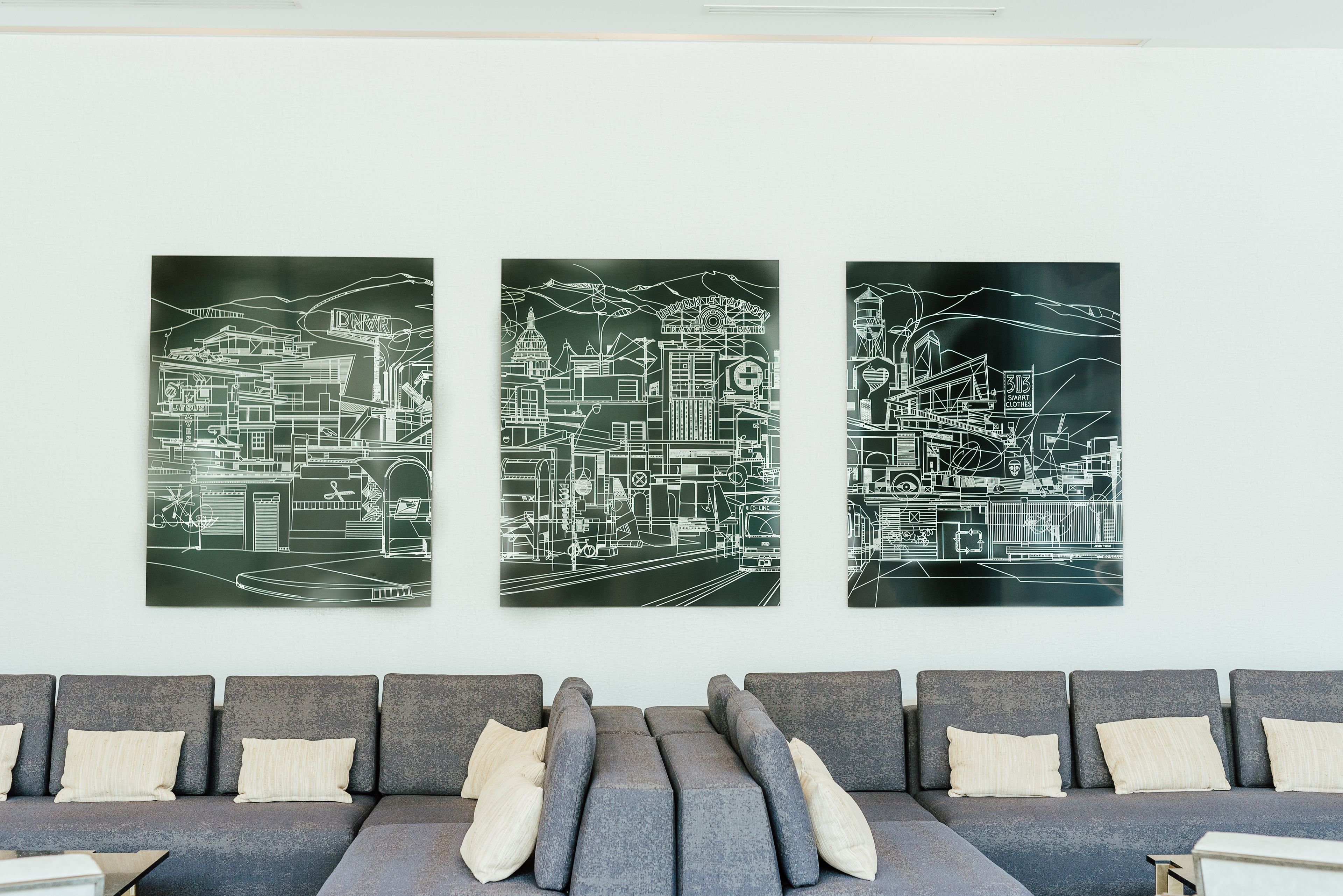 A modern living room with a grey sofa and a large wall-mounted artwork depicting a cityscape.