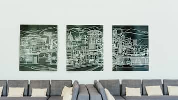 A modern living room with a grey sofa and a large wall-mounted artwork depicting a cityscape.