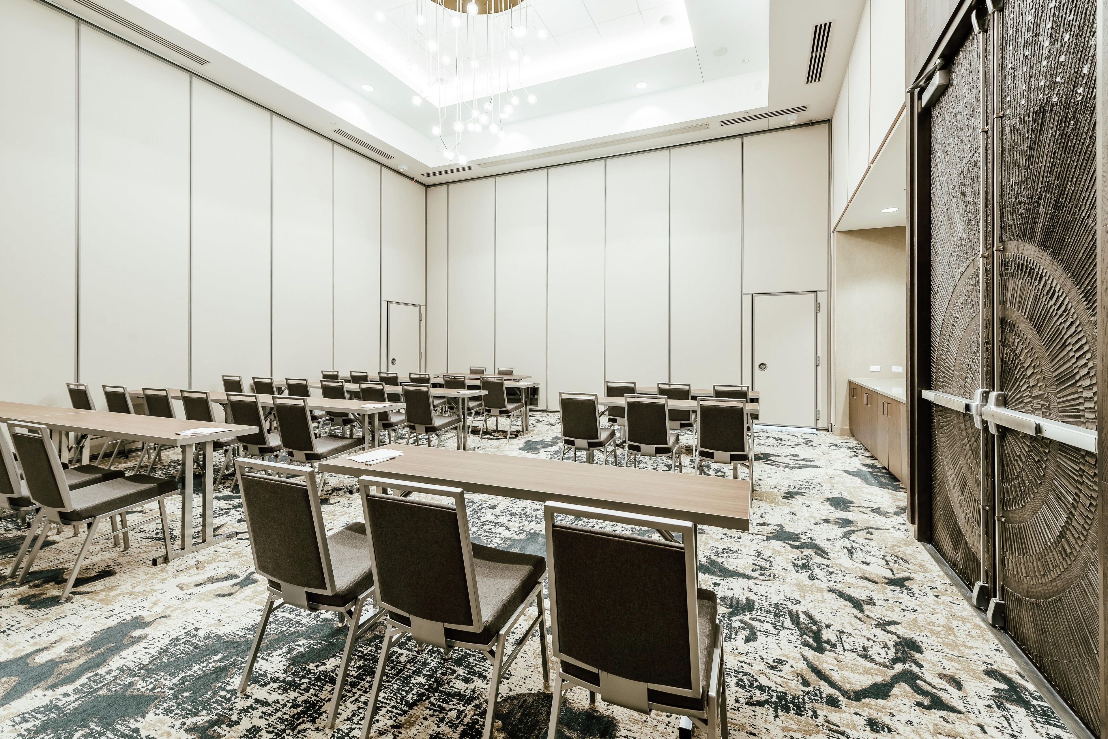 A conference room with multiple tables and chairs, a patterned carpet, and a decorative wall panel.