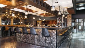 A modern bar area with a central island, bar stools, and pendant lighting. - Hilton Garden Inn Denver Union Station, CO (Denver)