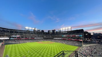 A large stadium with multiple levels of seating, a well-maintained field, and surrounding urban buildings.