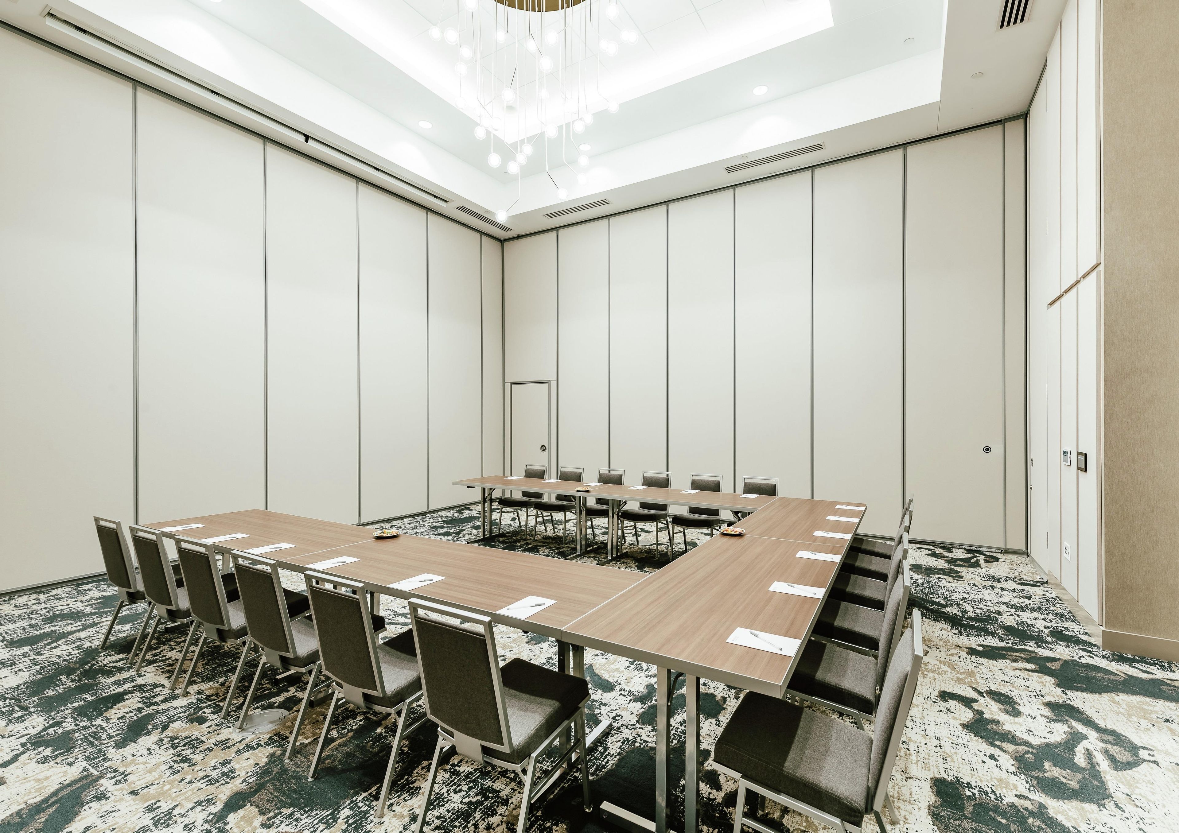 A conference room with a long table, chairs, and a patterned carpet.