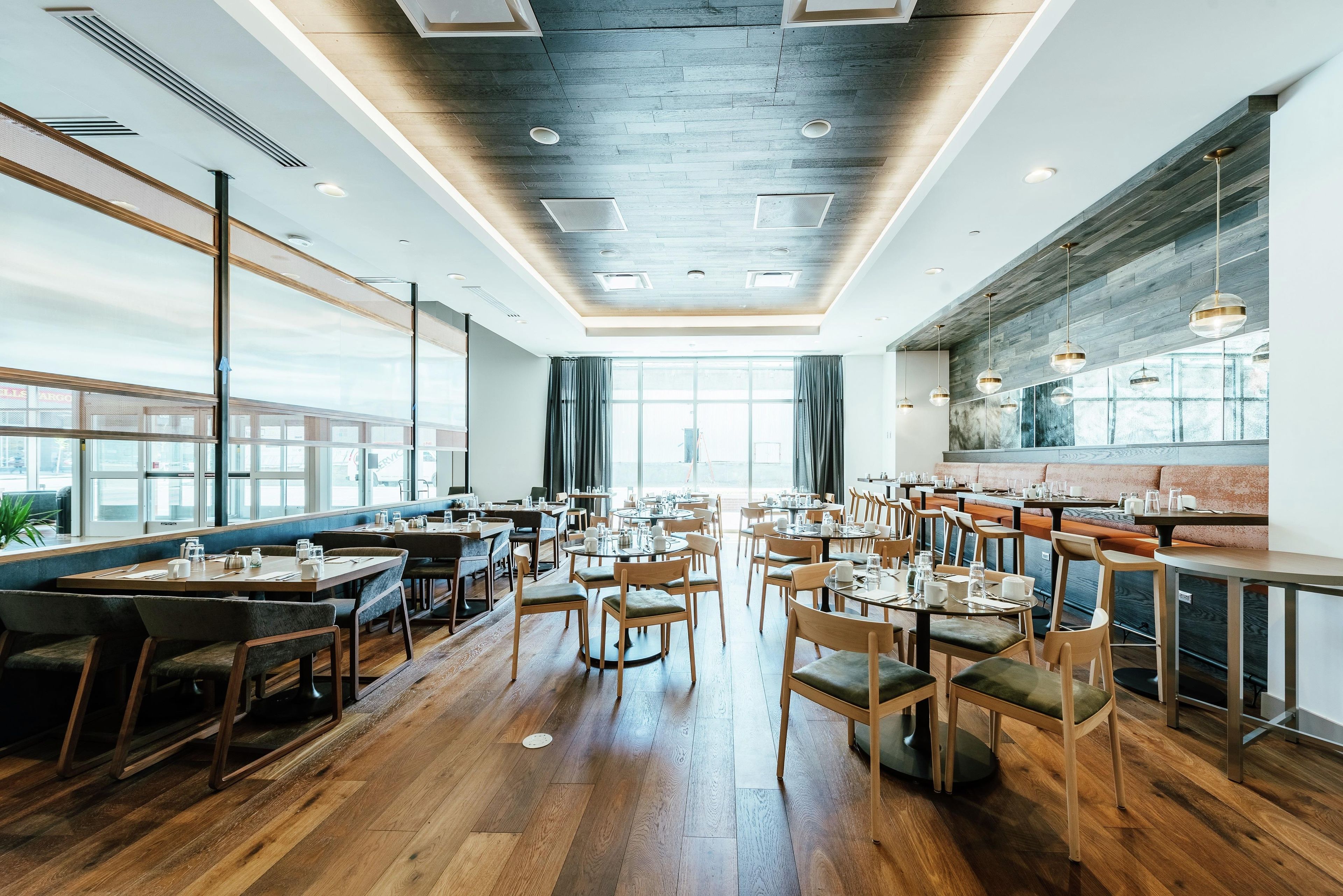 Un interior de restaurante moderno con piso de madera, varias mesas y sillas.