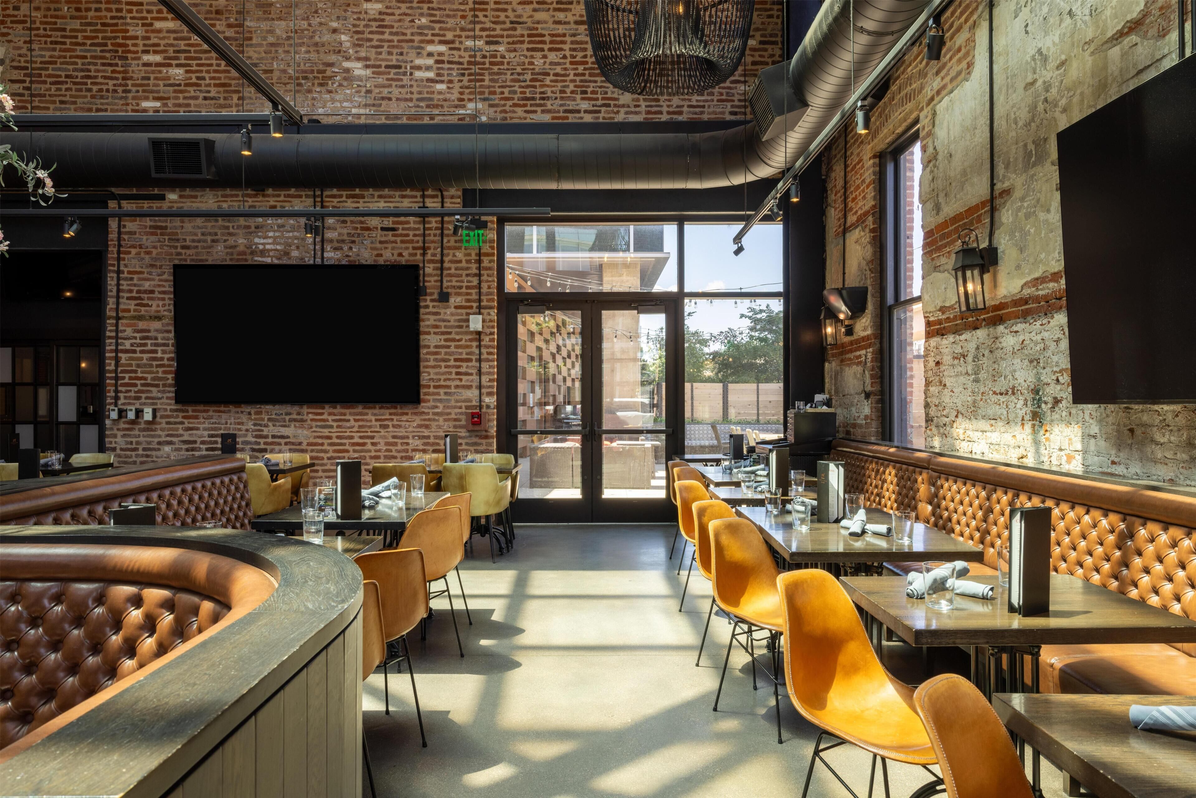 A restaurant with brick walls, leather booths, and a long counter.